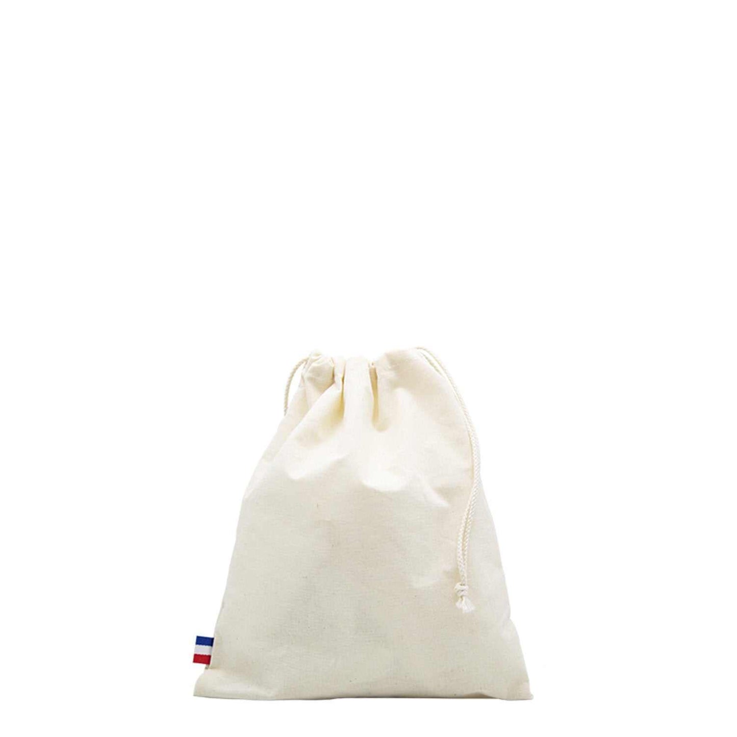Sac de plage en coton biologique GOTS, grand format, posé sur une serviette au bord de la mer avec accessoires de plage (lunettes, livre, crème solaire)
